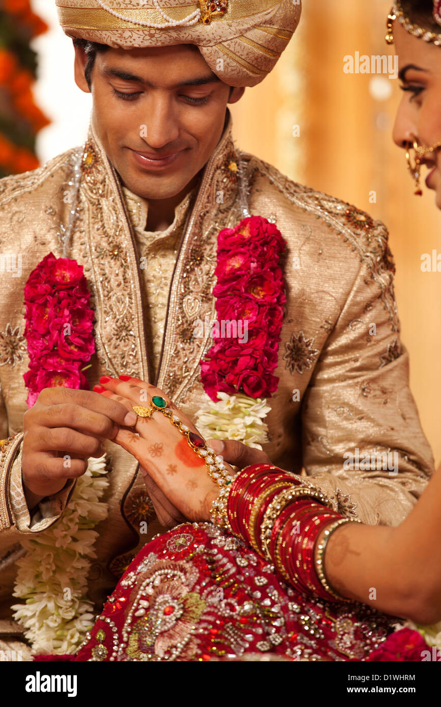 Indian novio poniendo un anillo de bodas de una novia Foto de stock