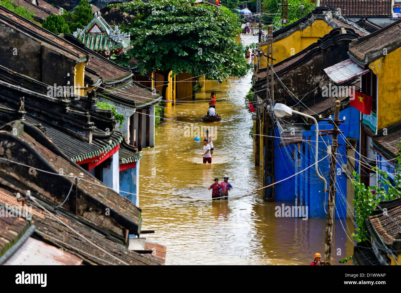 Calle inundada en la ciudad antigua de Hoi An, Vietnam con lugareños vadeando Foto de stock