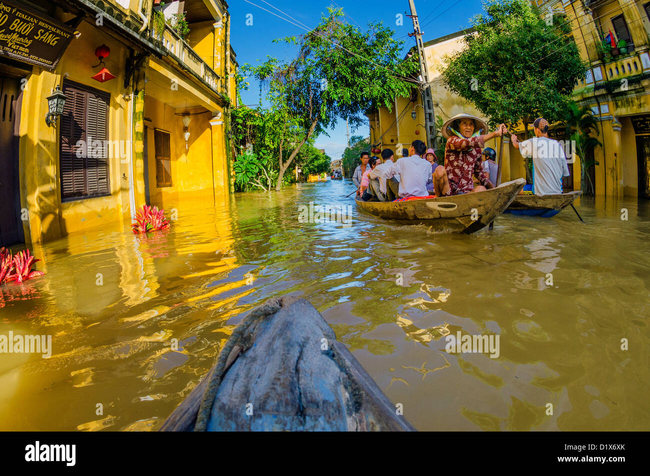 Los lugareños recorren las calles inundadas por barco, Hoi An, Vietnam Foto de stock
