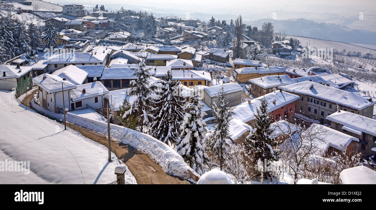 Panorama sobre la pequeña ciudad, carretera entre las casas y los techos cubiertos de nieve en la Diano D'Alba en el Piamonte, Norte de Italia. Foto de stock