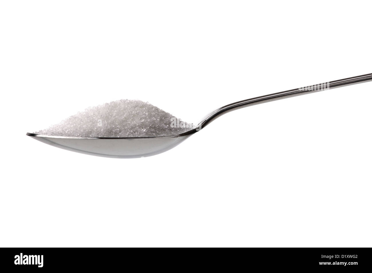 Azúcar o sal en una cucharadita. Foto de stock