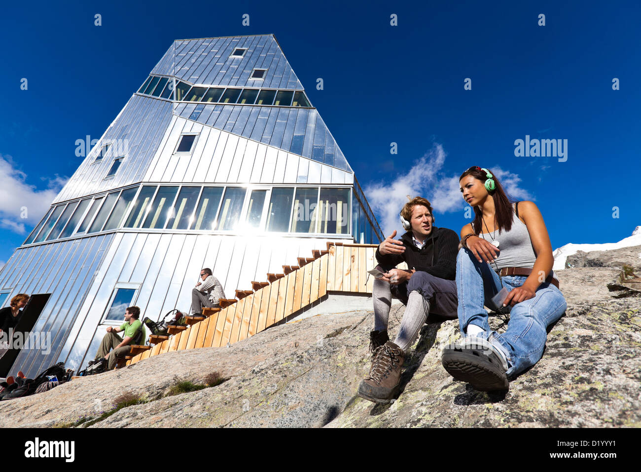 Dos jóvenes con auriculares en la parte delantera de la nueva Monte Rosa Hut, myclimate audio trail, Zermatt, Alpes Peninos, en el cantón de Valais, Foto de stock