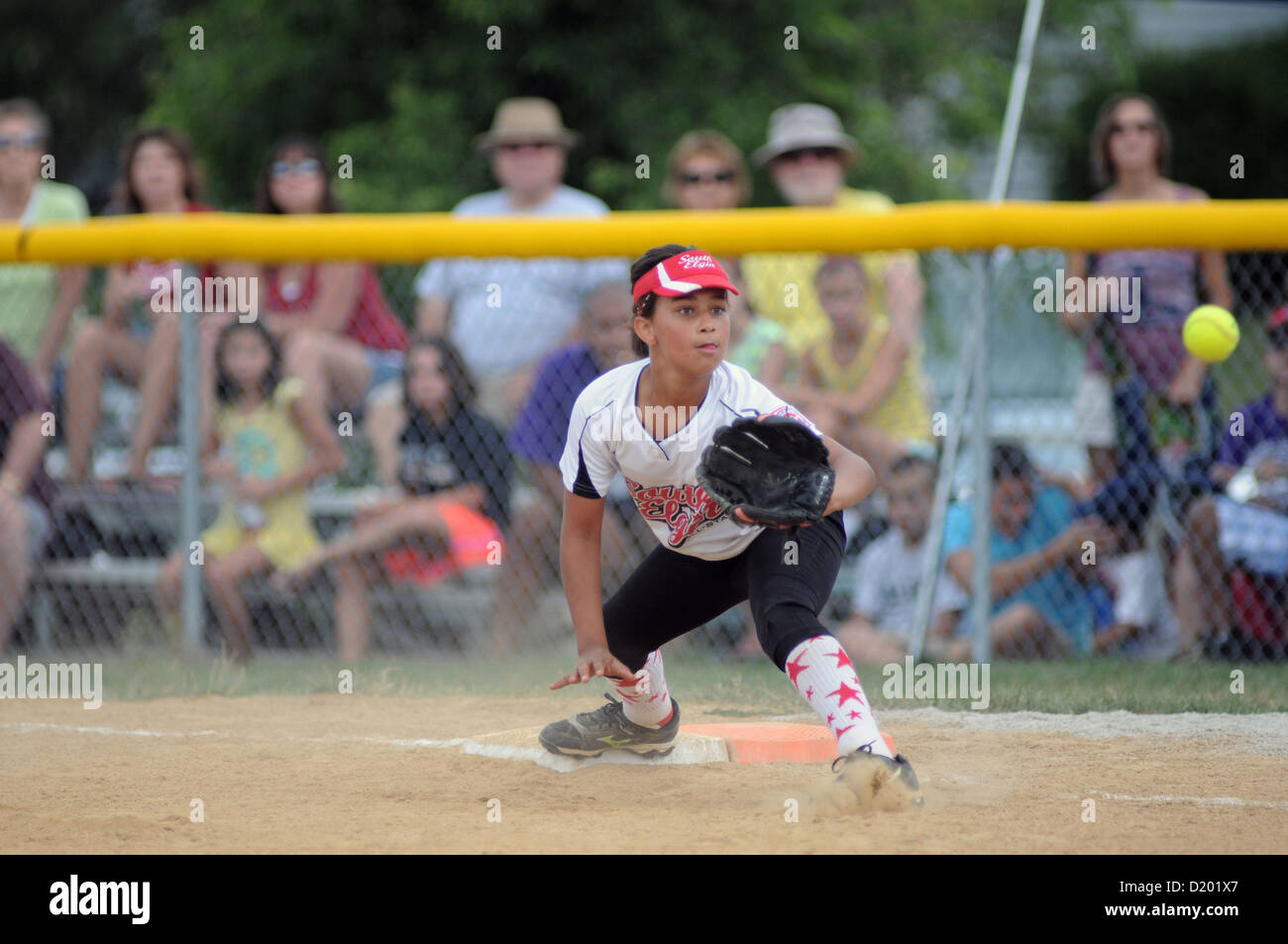 El softbol primer baseman estira para throw a jubilarse un bateador opuestos durante una Little League juego sancionado en el sur de Elgin, Illinois, EE.UU. Foto de stock