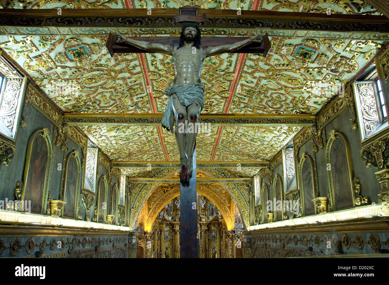 Un crucifijo y ensangrentado a Cristo en la iglesia de San Francisco de Quito, la capital del Ecuador, resta el ojo del glorioso techo Foto de stock
