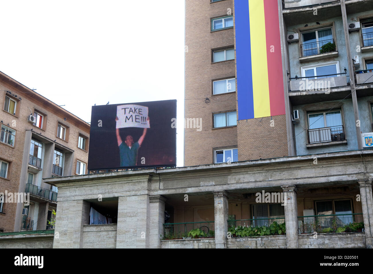 Bucarest, Rumania, una bandera del país y edificios residenciales con video wall Foto de stock