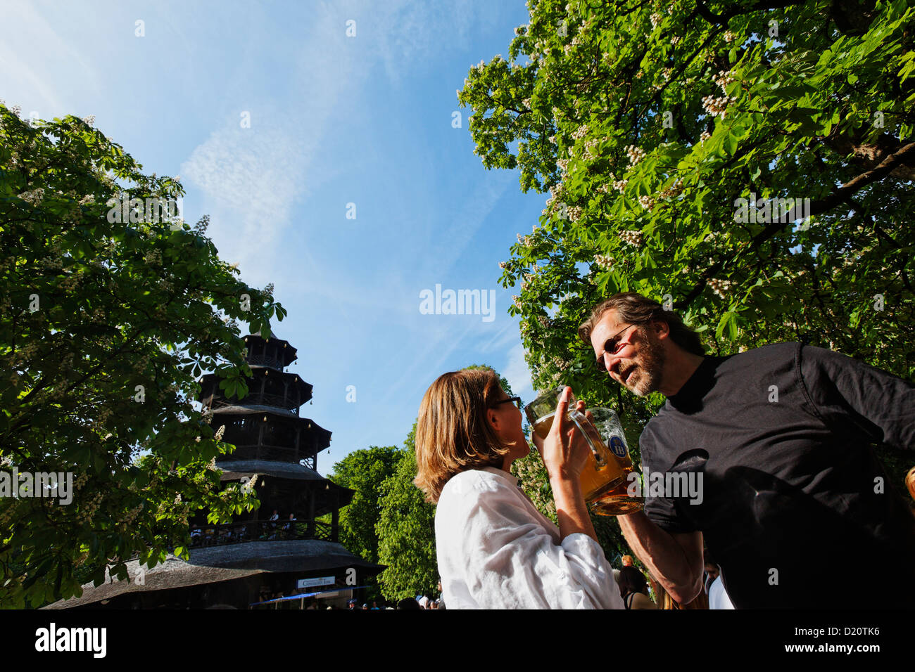 Gente disfrutando de un día soleado en el Chinesischer Turm beer garden, el Englischer Garten, Munich, la Alta Baviera, Baviera, Alemania, la Unión Europea Foto de stock