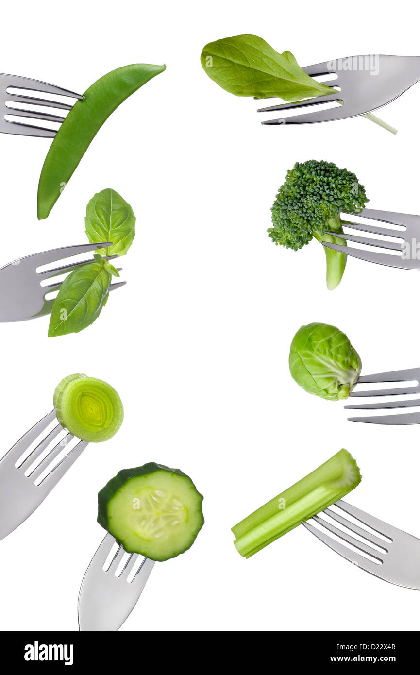 Borde de verduras verdes frescas en las horquillas aisladas contra un fondo blanco. Concepto de comida saludable Foto de stock