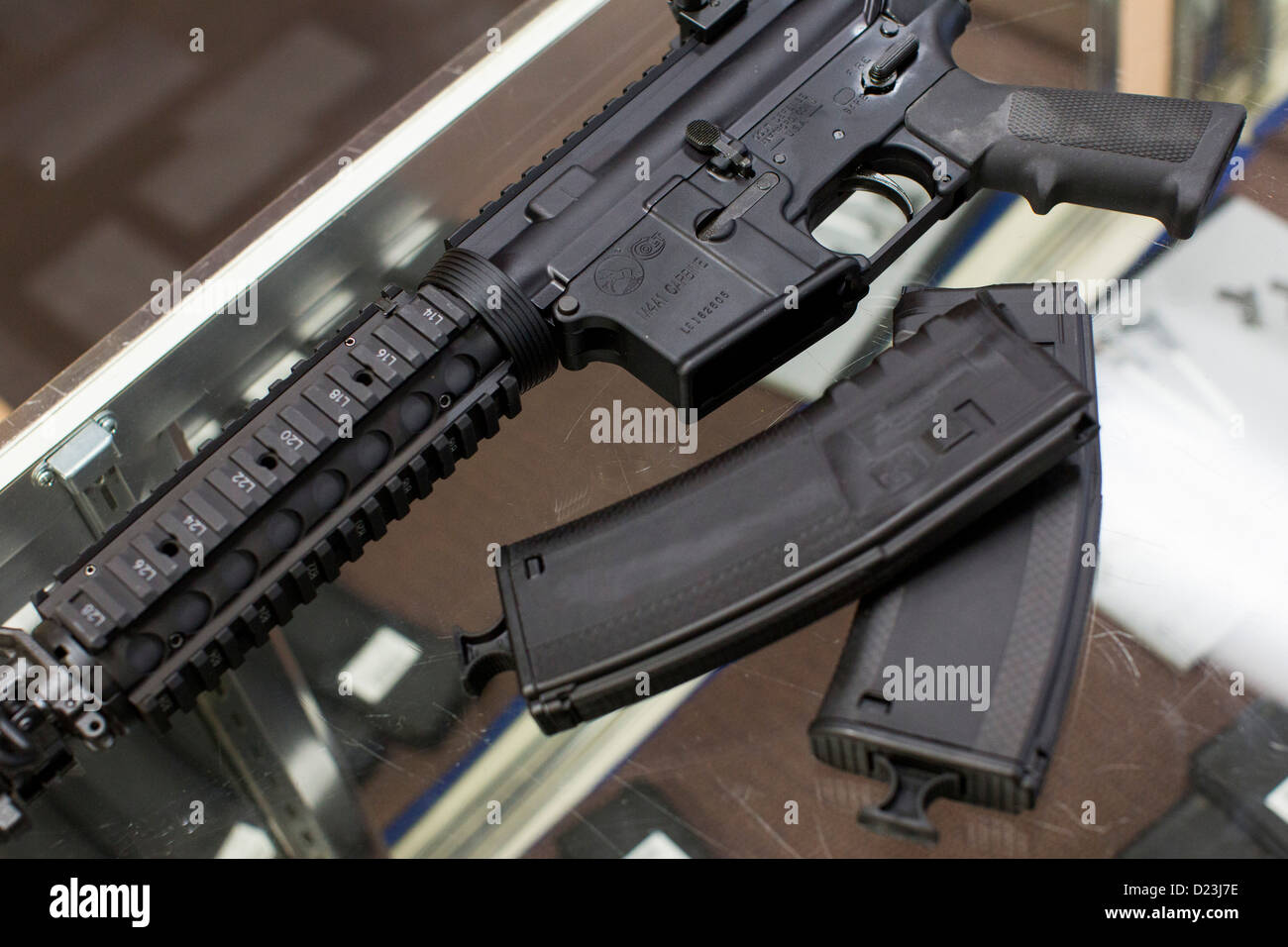 Una defensa Colt M4A1 Carbine rifle de asalto en la pantalla en una armería con alta capacidad 30 mesas revistas. Foto de stock