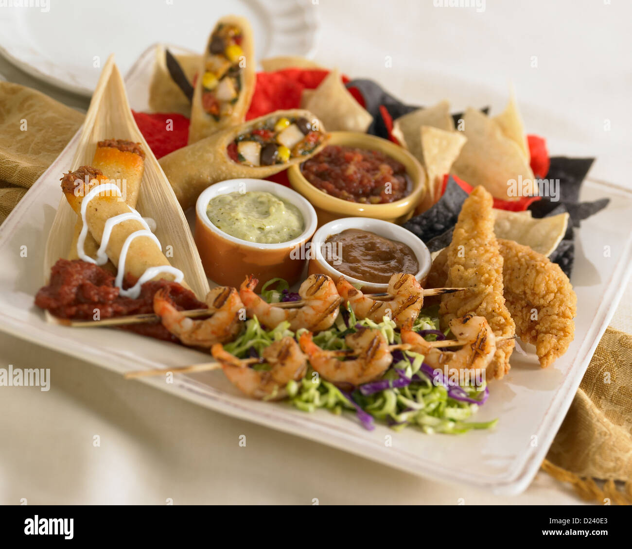 Plato aperitivo mexicano con brocheta de pollo, camarones, taquitos, patatas fritas y salsas Foto de stock