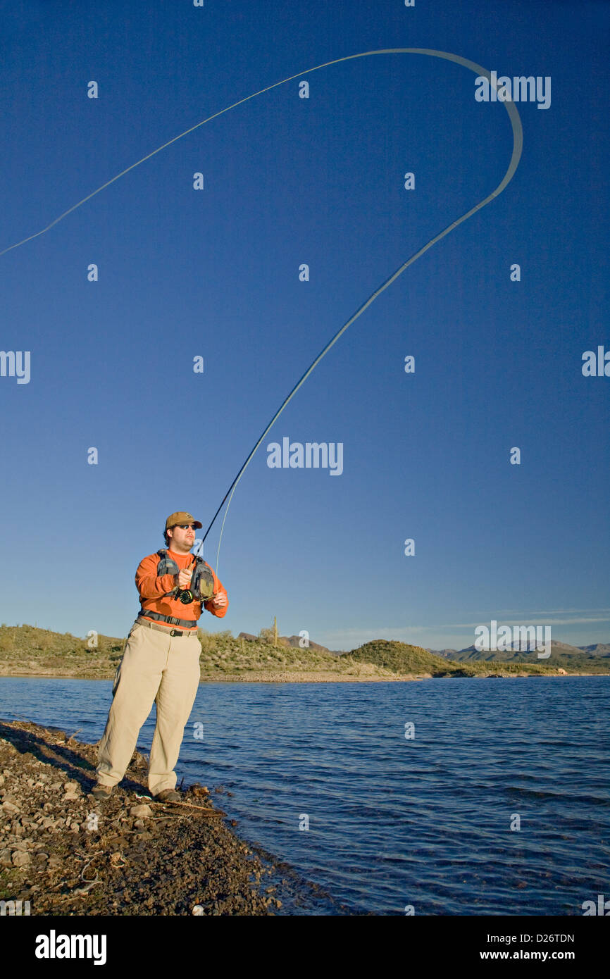 El hombre proyecta su línea de pesca con mosca en el lago Pleasant en Arizona Foto de stock