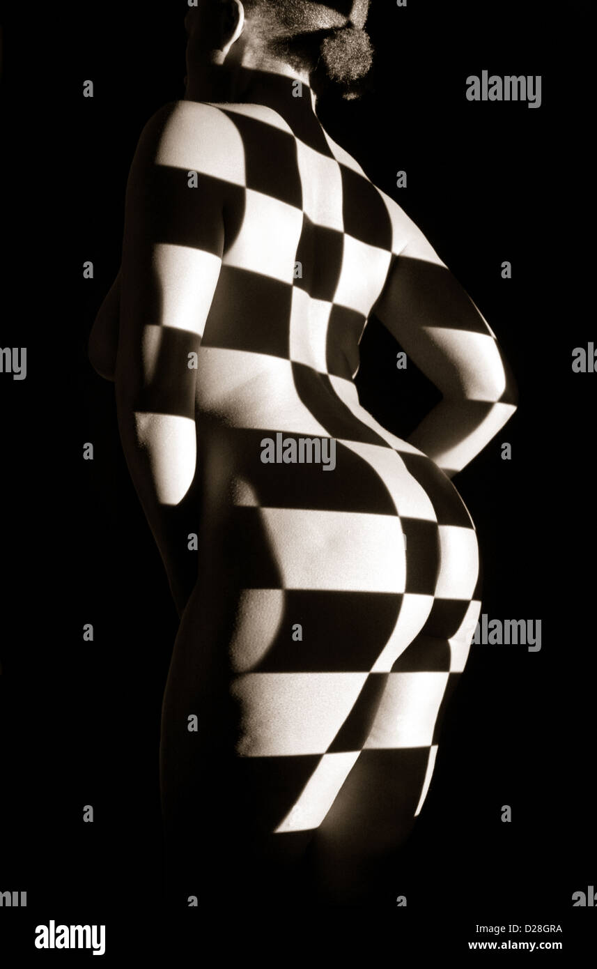 Proyección de tablero de ajedrez en la parte posterior e inferior de una joven mujer desnuda. Foto de stock