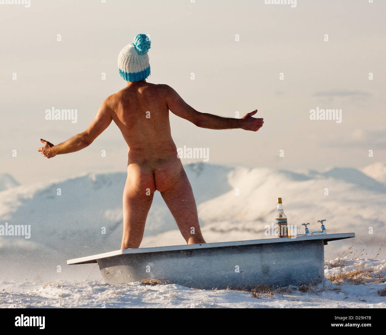 Hombre desnudo en la bañera en la cima de una montaña vistiendo woolly hat  durante invierno Escocés Fotografía de stock - Alamy