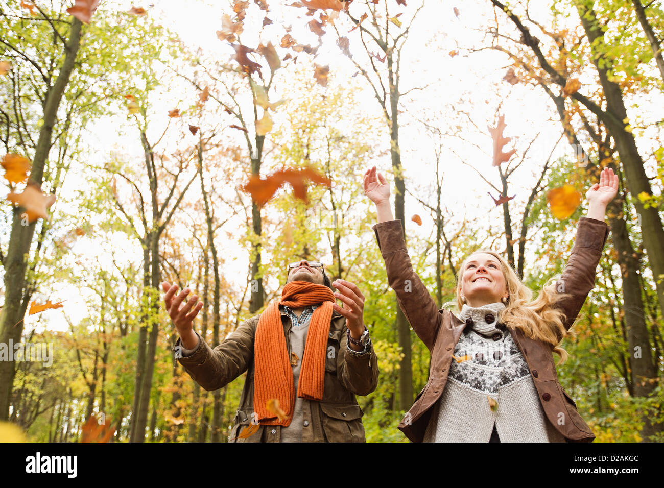 Pareja sonriente jugando en hojas de otoño Foto de stock