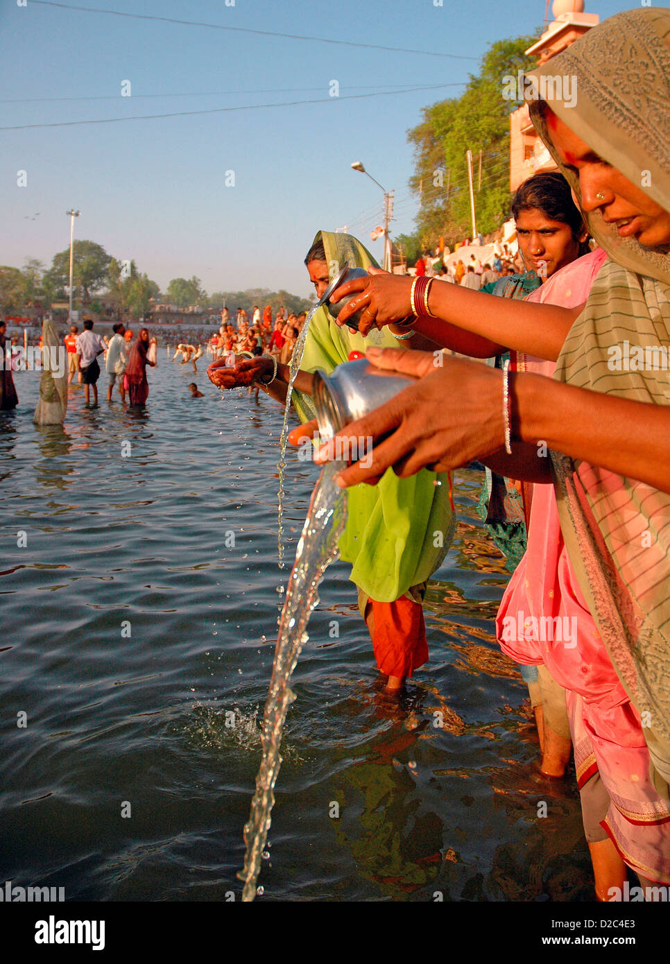 Mujer india orando por ofrecer agua a Dios Sol en los bancos del río Foto de stock