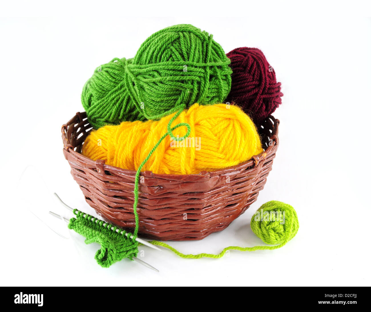 Hilados coloridos y agujas para tejer en cesta de mimbre Foto de stock