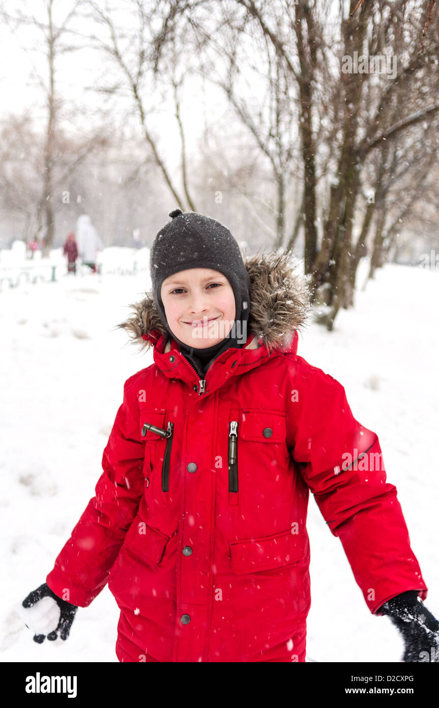 Sonriente niño usando chaqueta roja jugando con nieve Fotografía de stock -  Alamy