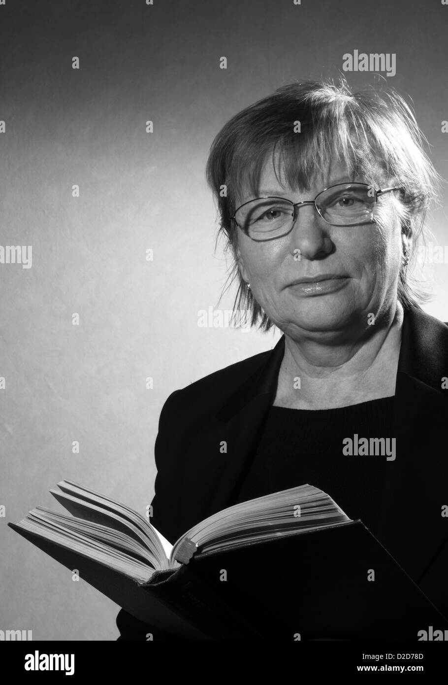 Retrato en blanco y negro de mujer de mediana edad en anteojos con el libro Foto de stock