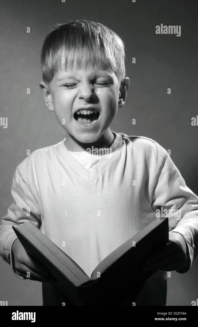 Retrato en blanco y negro de cute little boy con libro risas Foto de stock