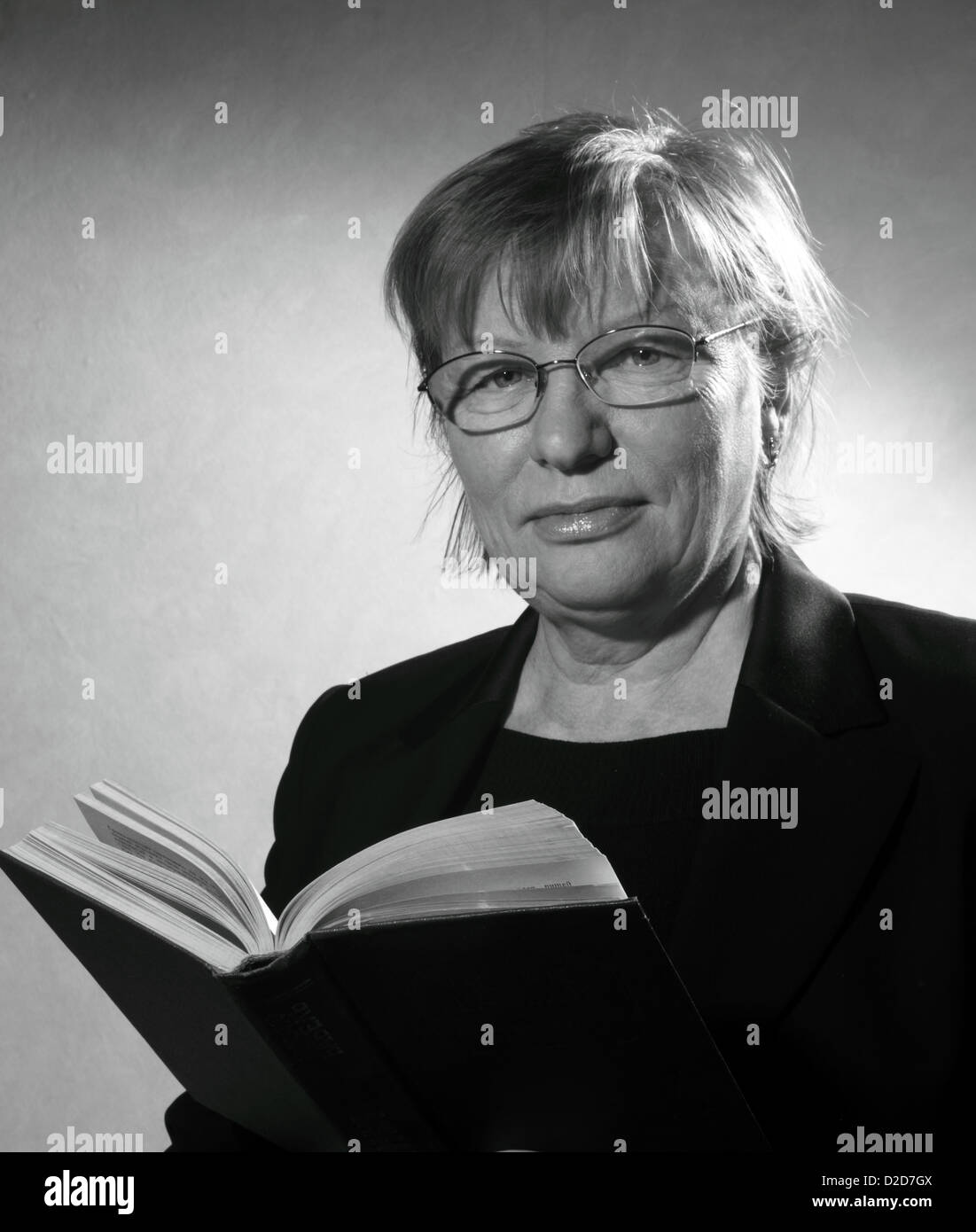Retrato en blanco y negro de mujer de mediana edad en anteojos con el libro Foto de stock