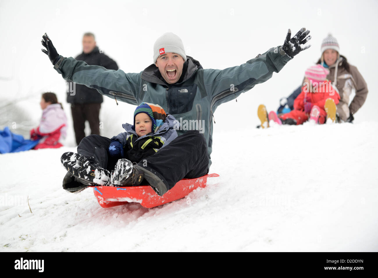 Padre e hijo trineos en Shropshire. Invierno nevado Gran Bretaña condiciones meteorológicas inviernos británicos diversión familia trineos Foto de stock