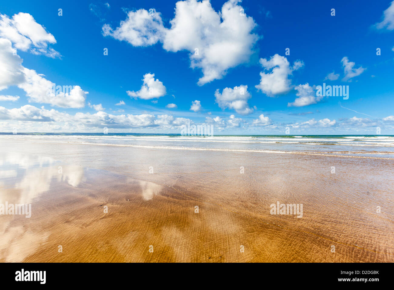 Playa vacía con esponjosas nubes reflejadas en la arena mojada, Saunton Sands en North Devon, Reino Unido. Foto de stock