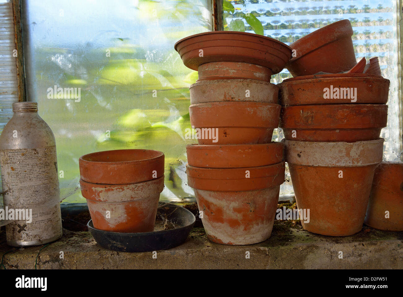 Antigua planta ollas vacías apiladas por ventana en una barraca del jardín Foto de stock