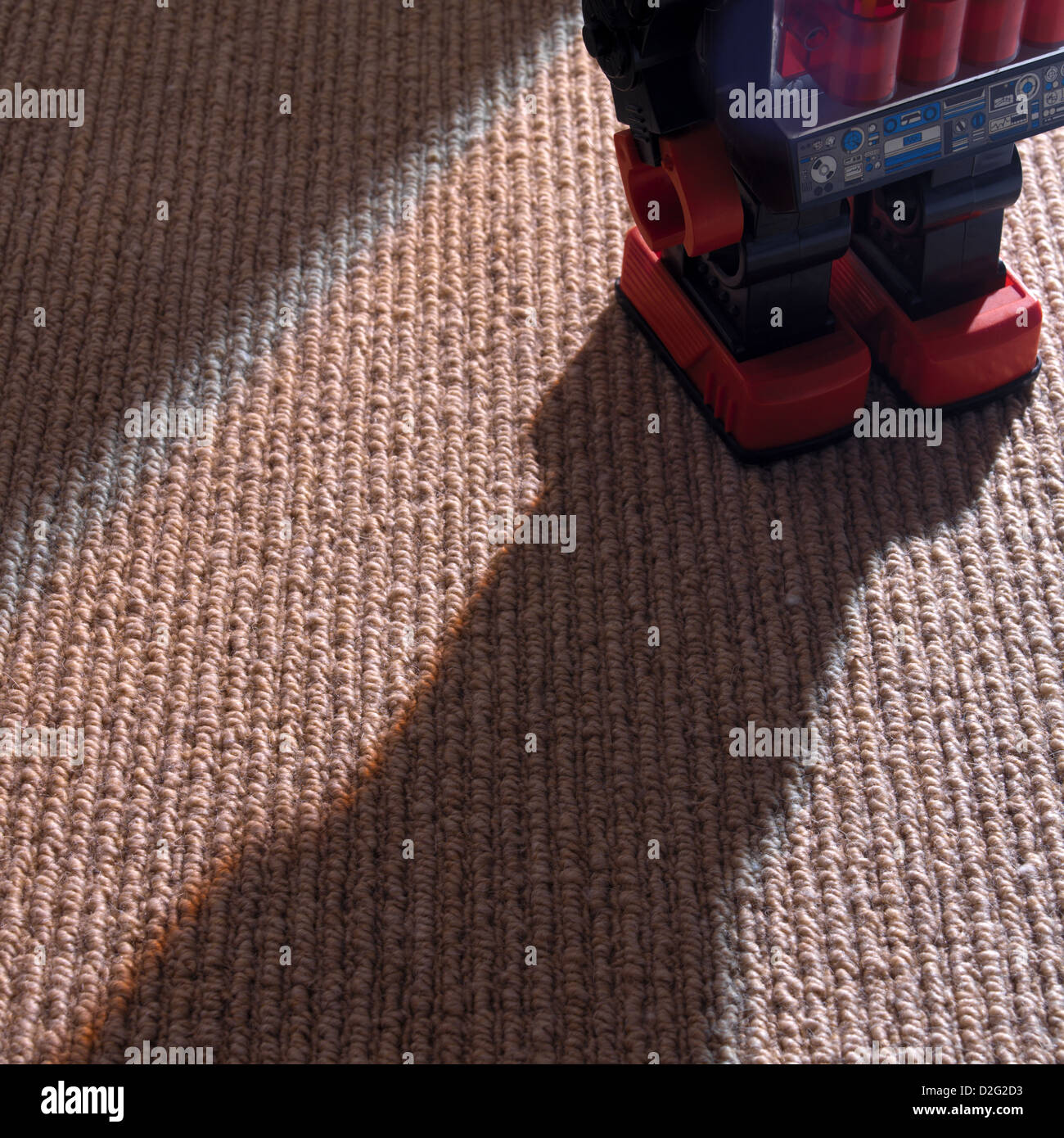 Robot de juguete en alfombras,larga sombra Foto de stock