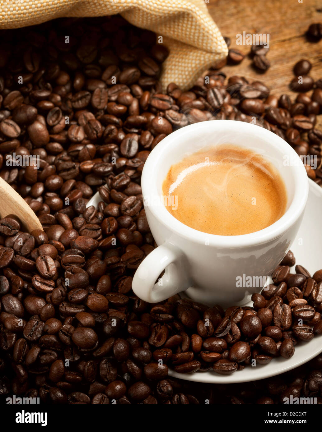 Taza de café caliente con granos de café sobre la mesa de madera Foto de stock
