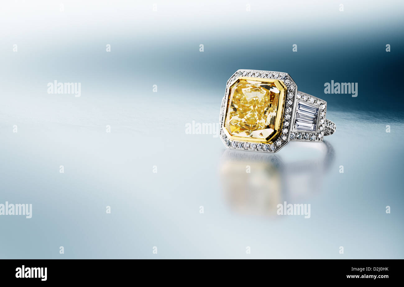 Anillo de diamantes canario amarillo sobre fondo plateado azul Foto de stock