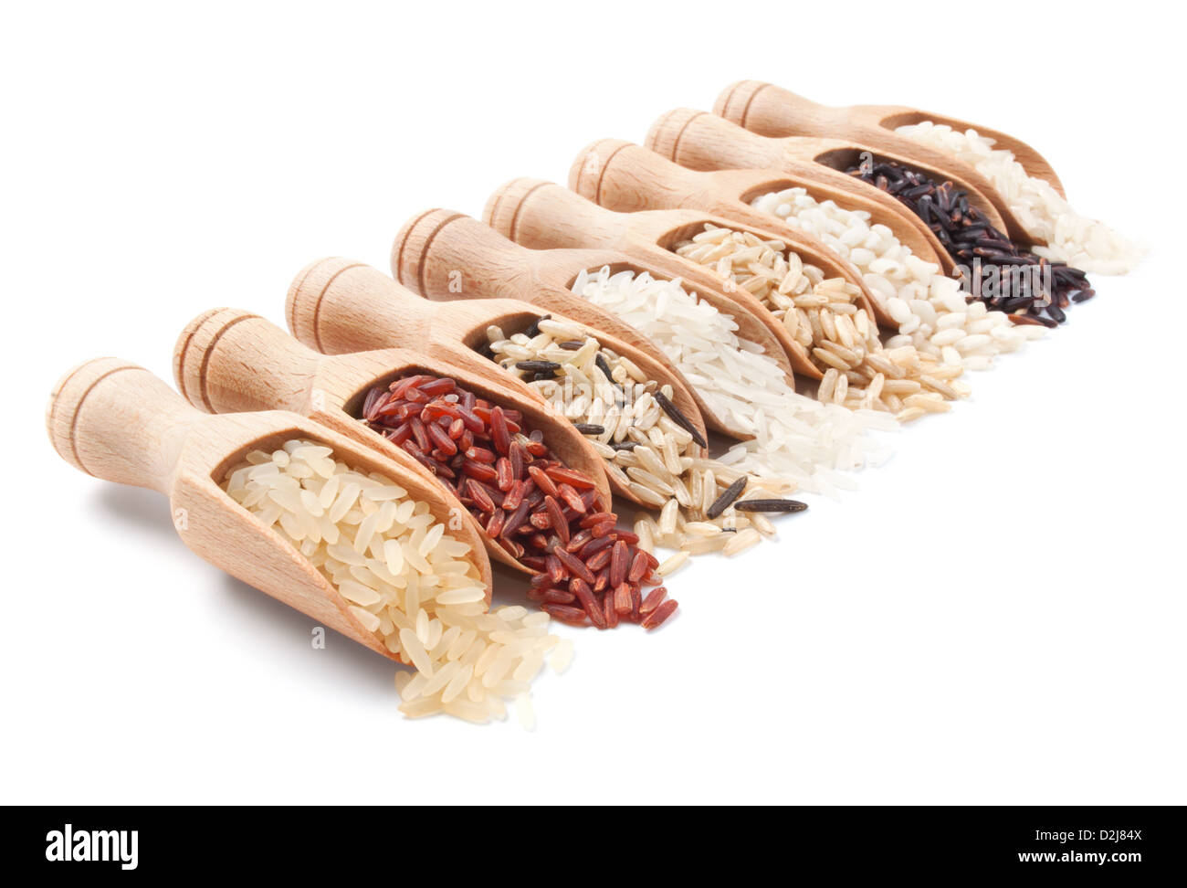 Cucharas de madera con diferentes tipos de arroz esparcidos de ellos sobre fondo blanco. Foto de stock