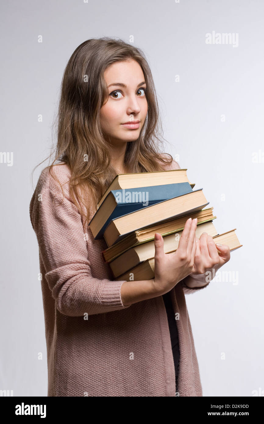 Conmocionado busca mujer joven morenita con gran montón de libros. Foto de stock