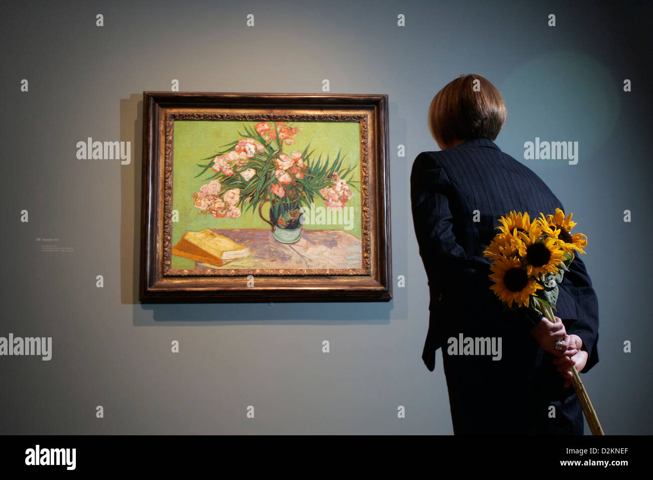 Una mujer sosteniendo los girasoles mira el 1888 pintura, 'Adelfas', de Vincent van Gogh Foto de stock