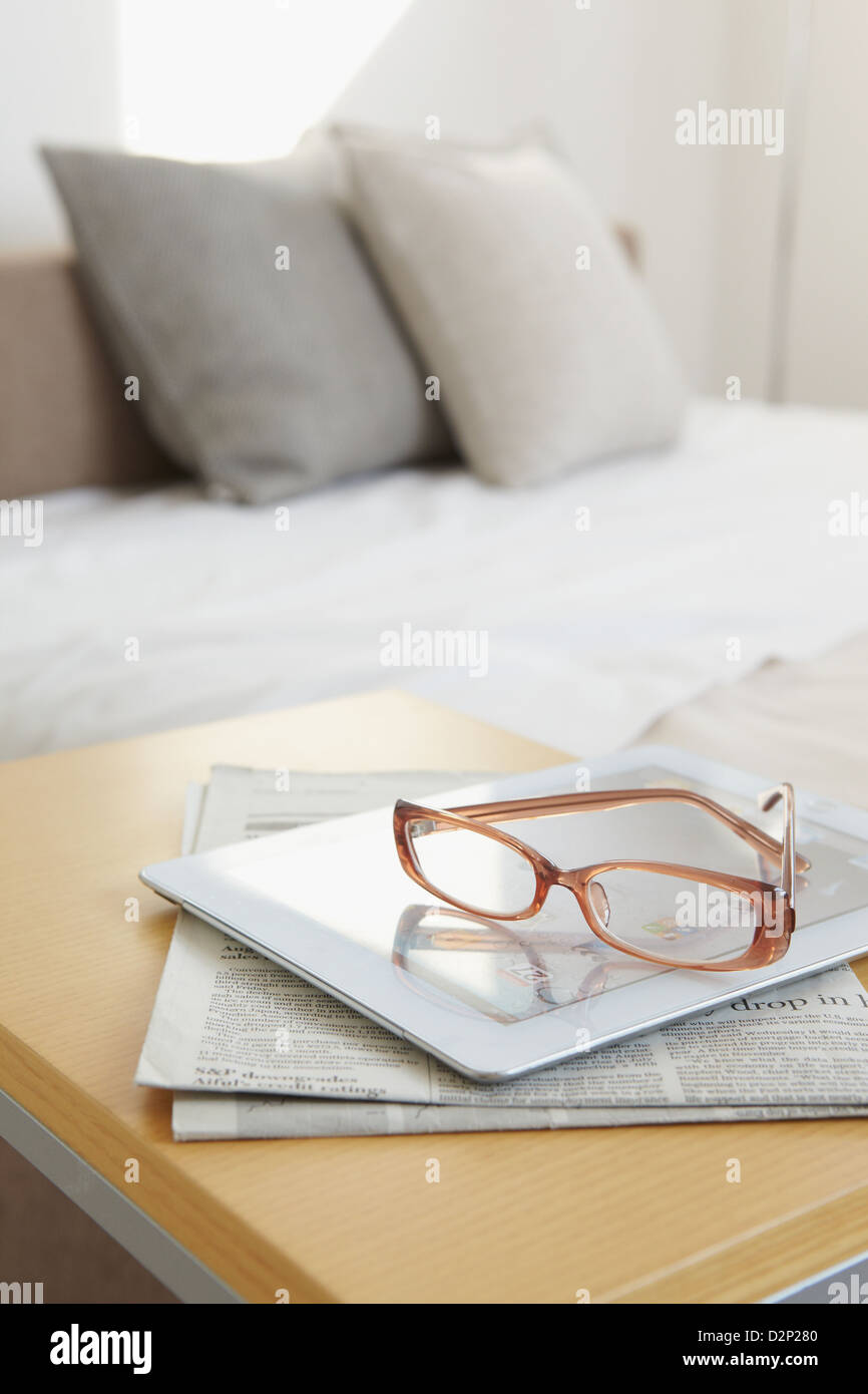 Gafas de tabletas y periódico sobre la cama Foto de stock