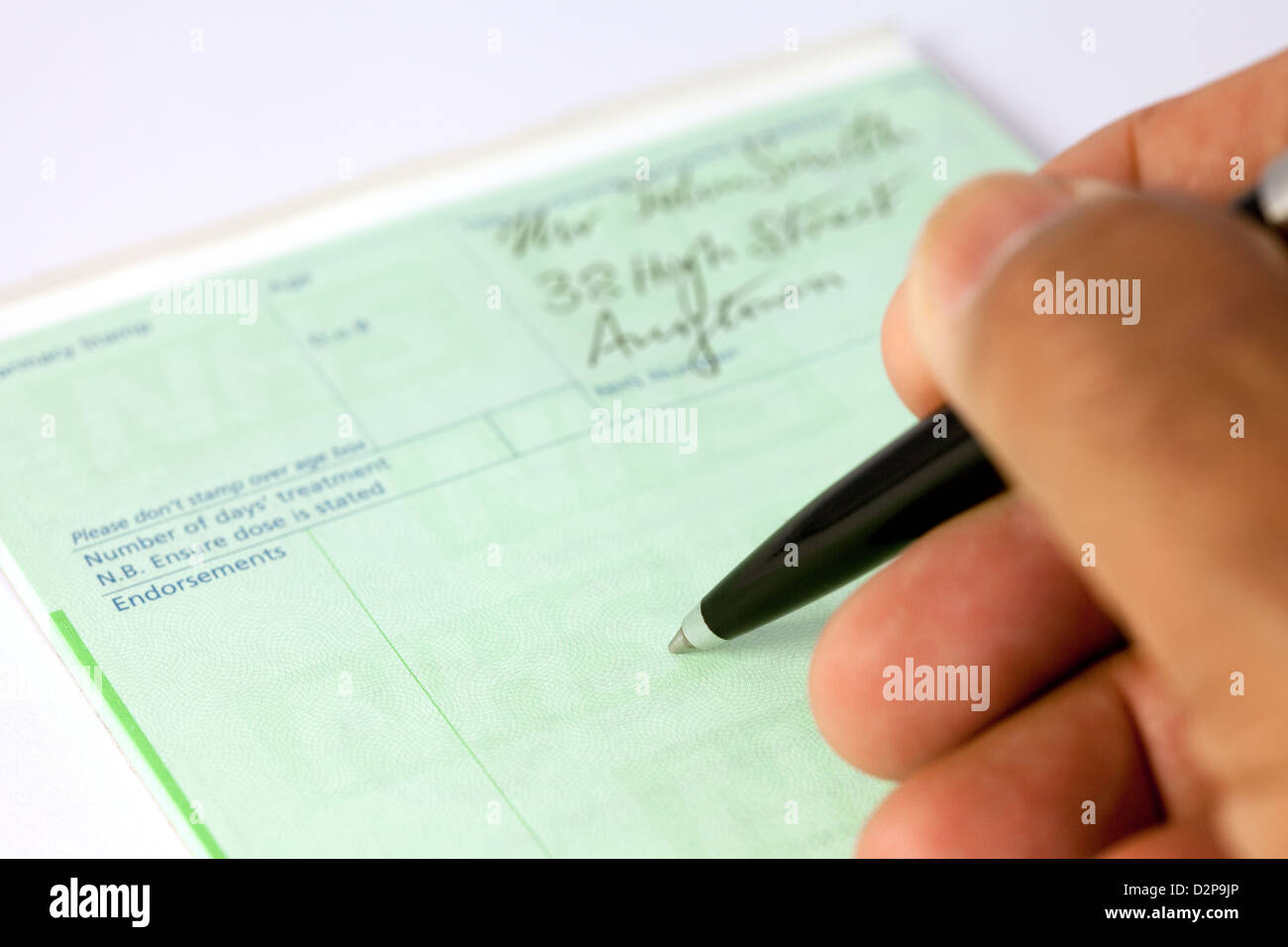 Un médico escribir una receta para los medicamentos en sus prescripciones para un paciente en el NHS, REINO UNIDO Foto de stock
