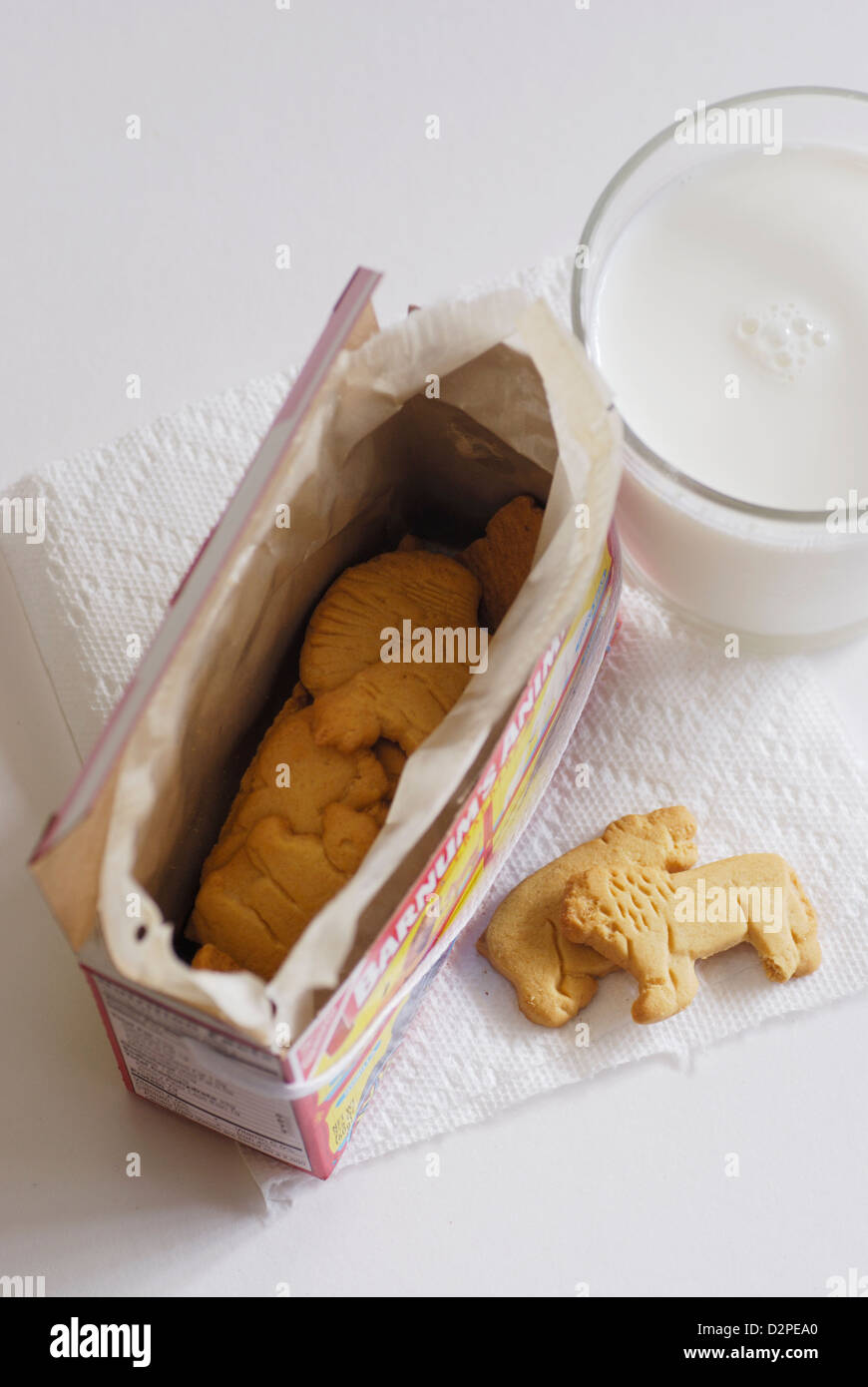 Galletas de animales con un vaso de leche de vaca en una servilleta de papel blanco vista superior con caja Foto de stock