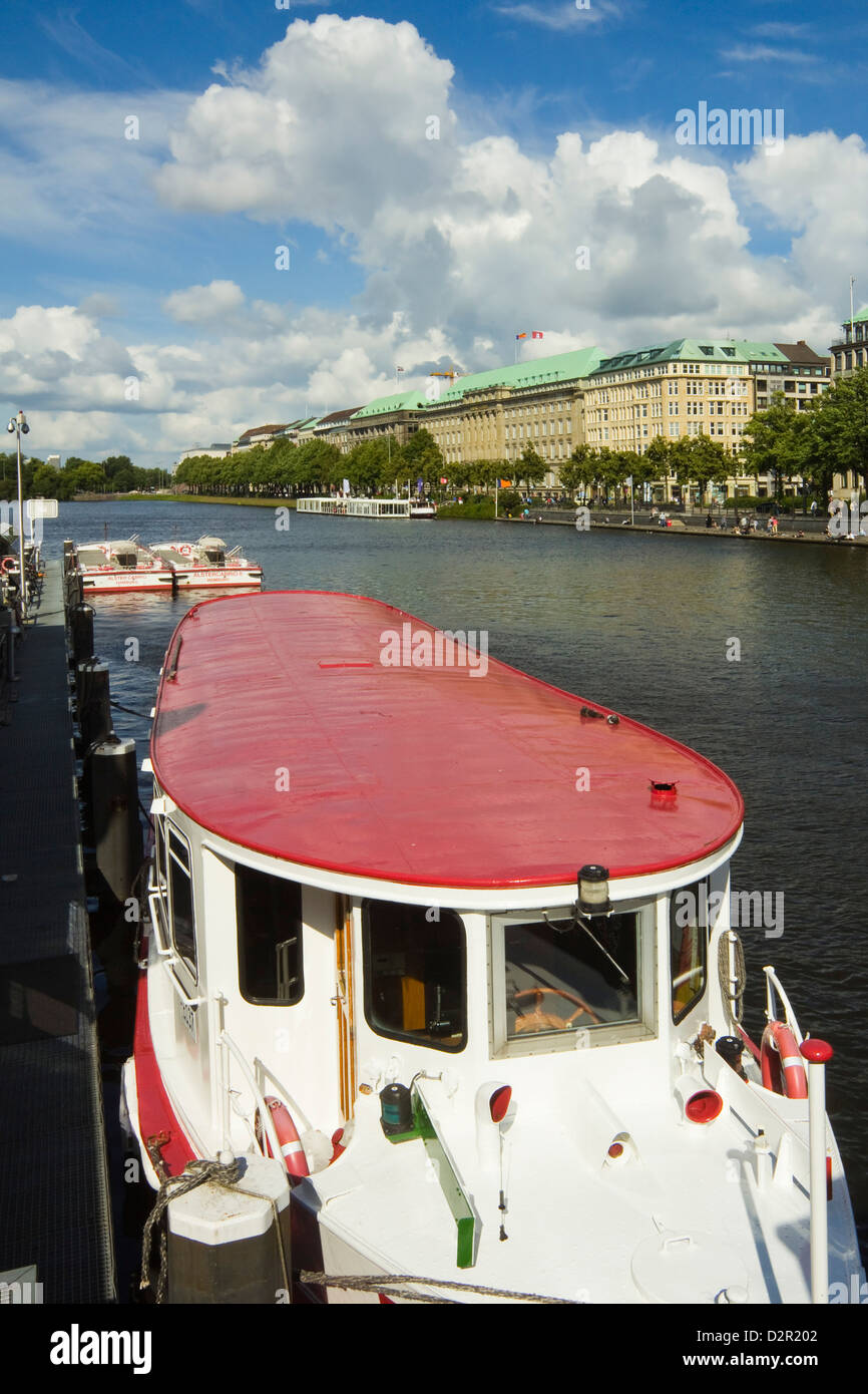 Uno de los barcos turísticos que surcan el lago Alster, amarrados en el Jungfernstieg con la Ballindamm más allá, Hamburgo, Alemania. Foto de stock