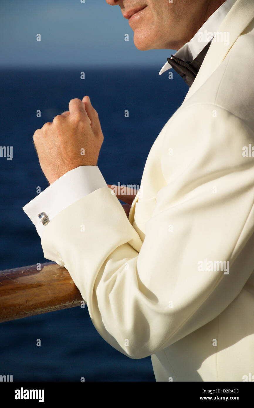 El hombre en el traje de noche se situó en los rieles de un buque de crucero Foto de stock
