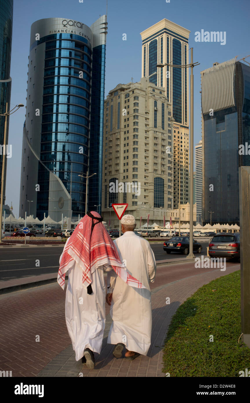 Los hombres en traje tradicional caminando en el distrito financiero de West Bay, Doha, Qatar Foto de stock