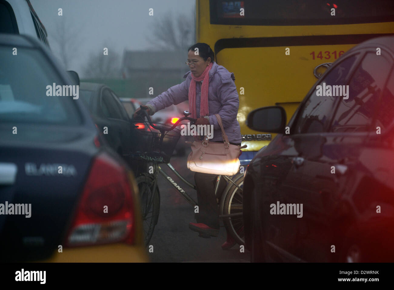Una mujer que monta una bicicleta en los vehículos lío en Beijing, China. 30-Jan-2013 Foto de stock