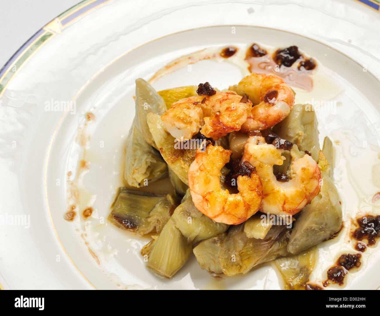 Alcachofas con gambas salteadas con cebolla caramelizada Foto de stock