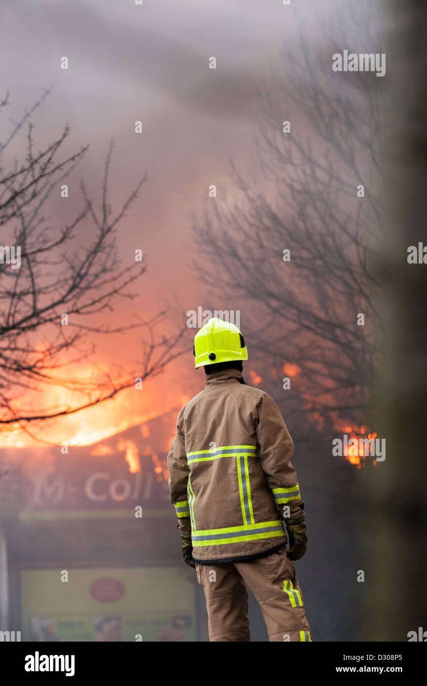 Bombero evaluar un ardiente shop edificio resplandeciente en Inglaterra, Reino Unido. Foto de stock