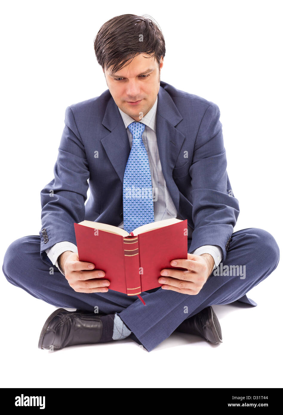 Hombre de negocios sentado con las piernas cruzadas y leer sobre fondo blanco. Foto de stock