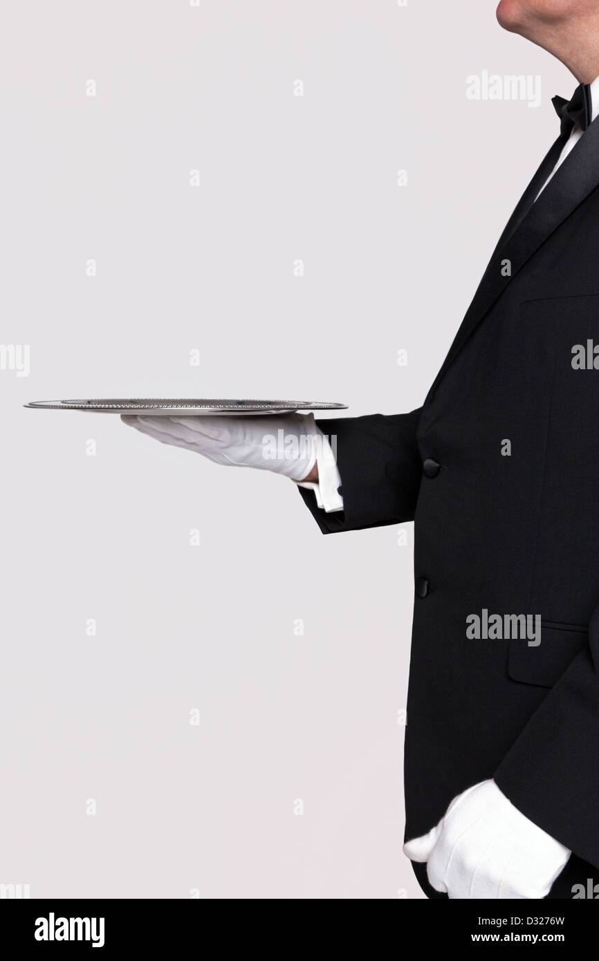 Vista lateral de un mayordomo sosteniendo una bandeja de servicio de plata, fondo blanco para agregar su propio producto. Foto de stock