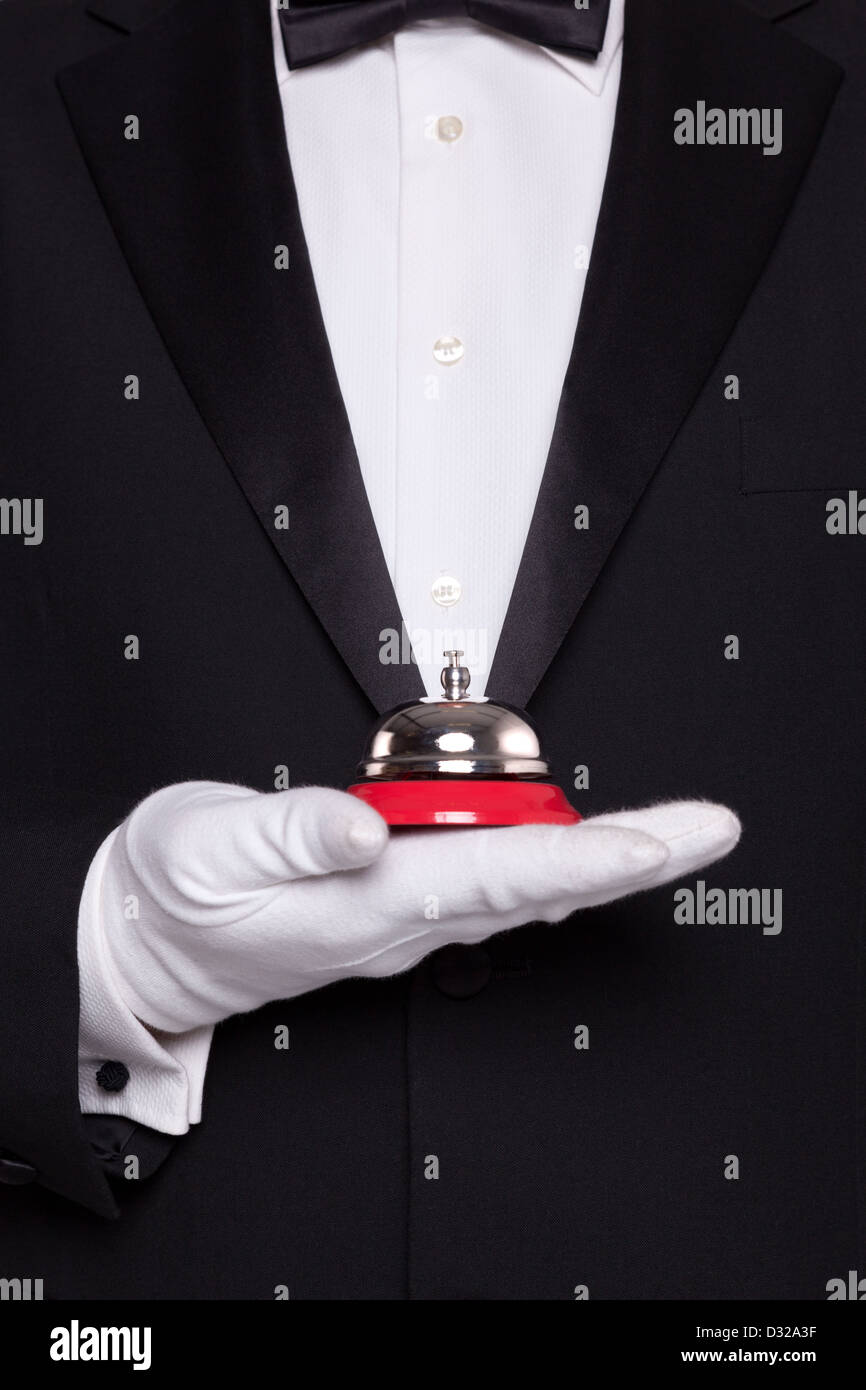 Camarero en black tie y guantes blancos sosteniendo un servicio Bell. Foto de stock