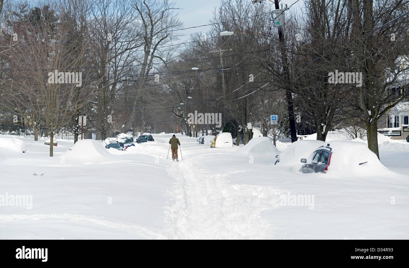 Newhaven, Connecticut, EE.UU. El 9 de febrero de 2013. Hombre esquís de travesía calle abajo con coches enterrado tras la tormenta de nieve Nemo cae de 34 centímetros de nieve en New Haven, CT. Crédito: Michael Doolittle / Alamy Live News Foto de stock