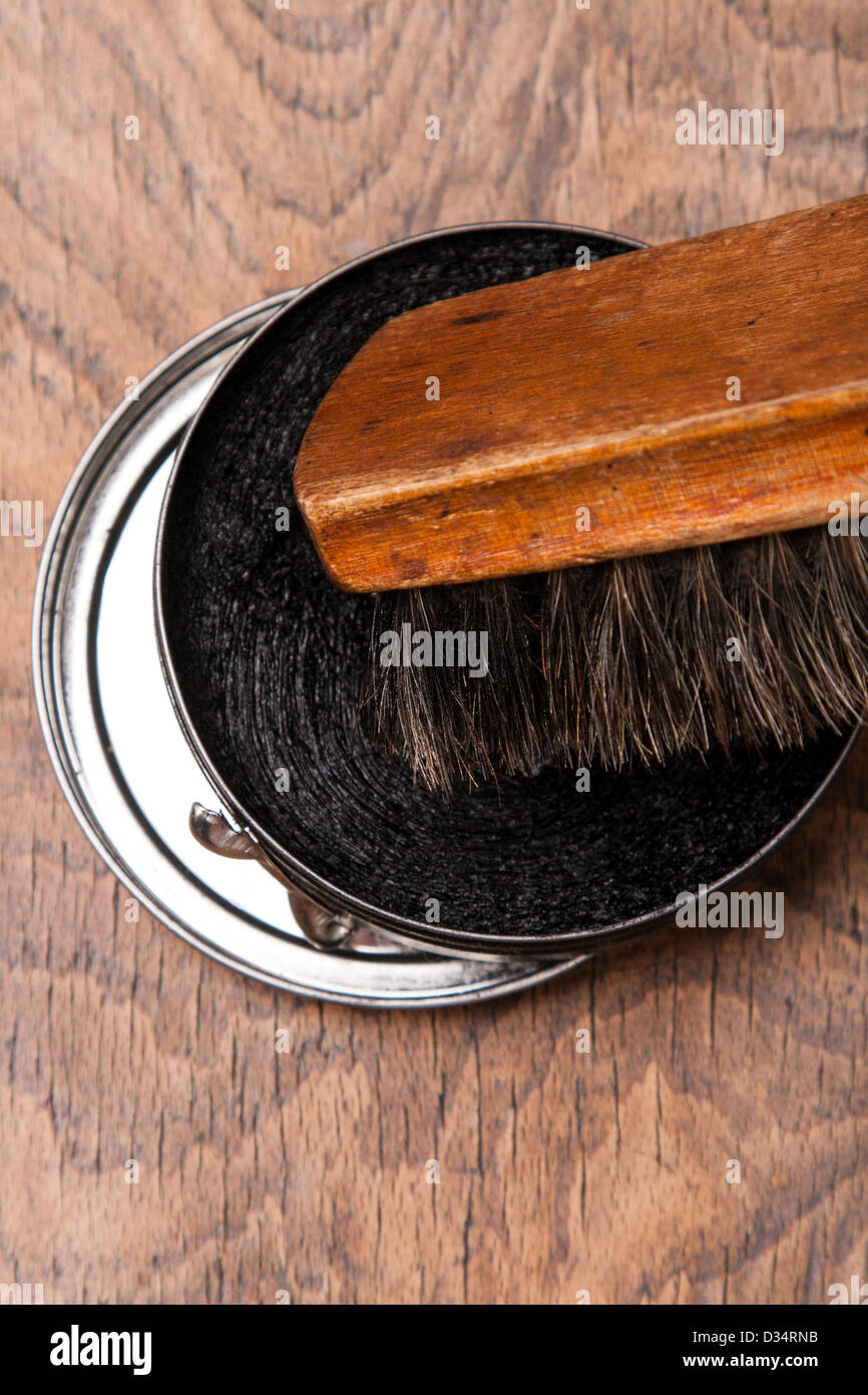 Contenedor de betún y cepillo sobre fondo de madera Foto de stock