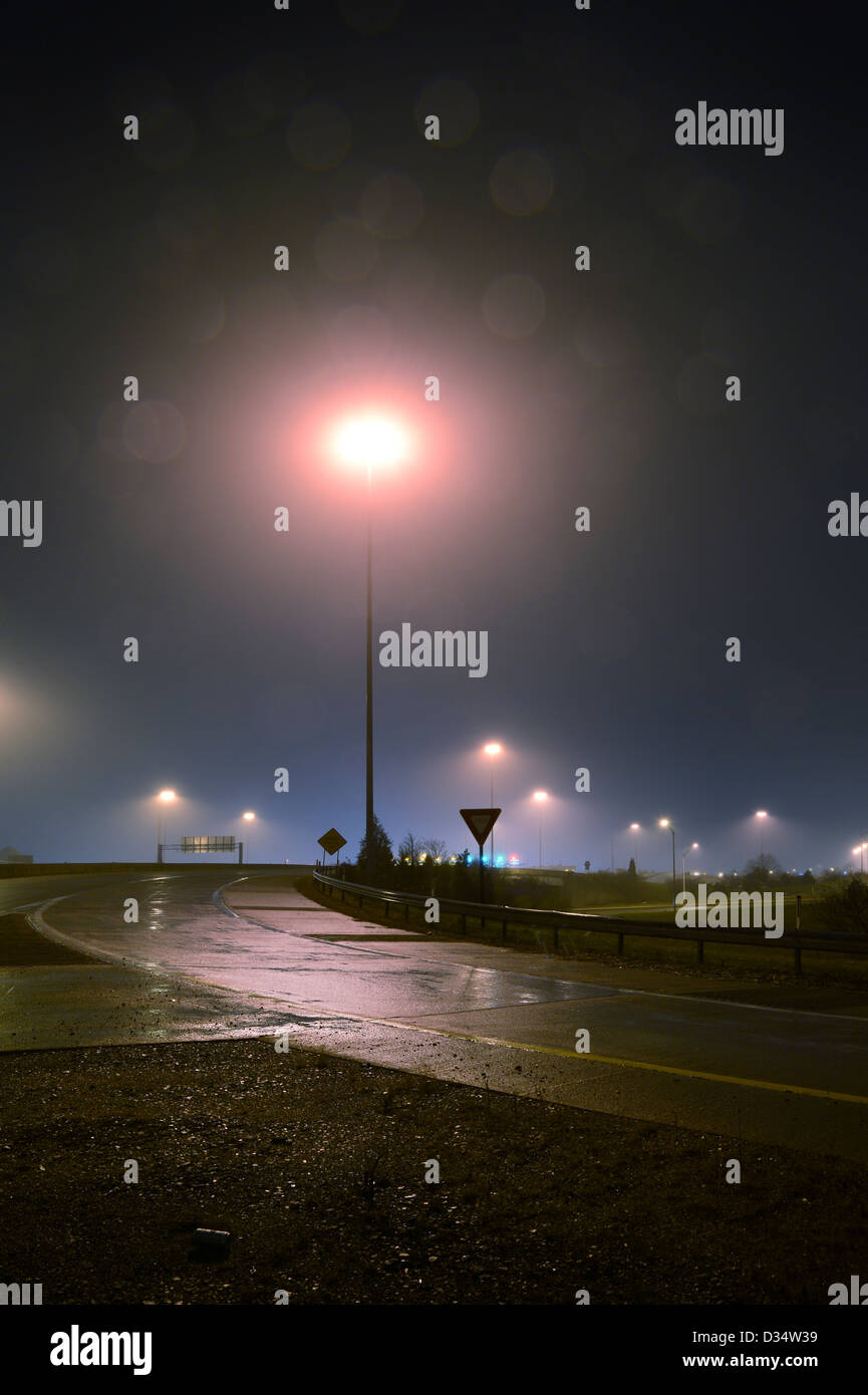La rampa de la autopista por la noche en la lluvia la niebla con poste de la luz Foto de stock