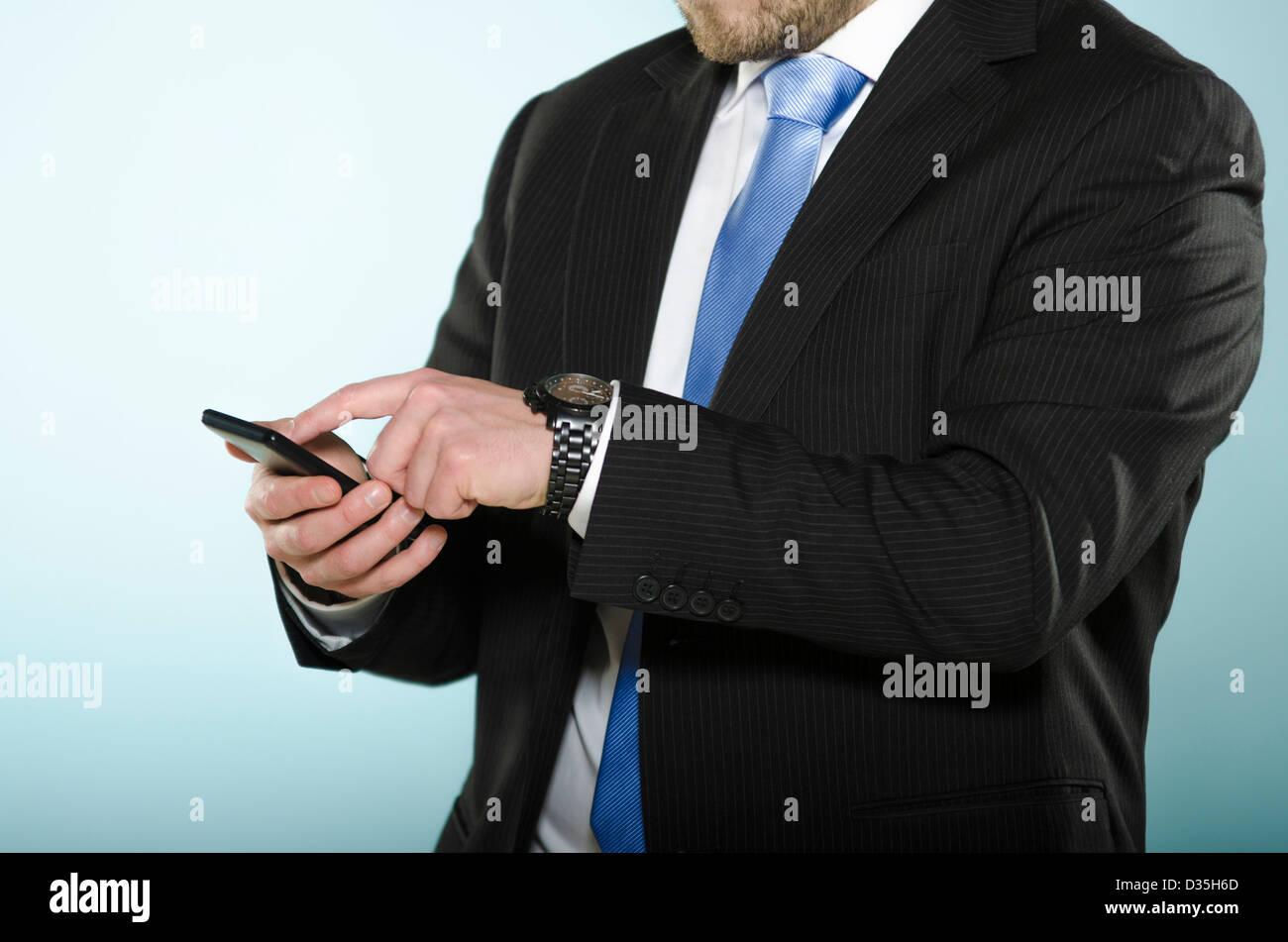 Empresario utilizando smart phone. Sección central de casualmente adaptados al hombre utilizando un teléfono de pantalla táctil con su dedo. Foto de stock