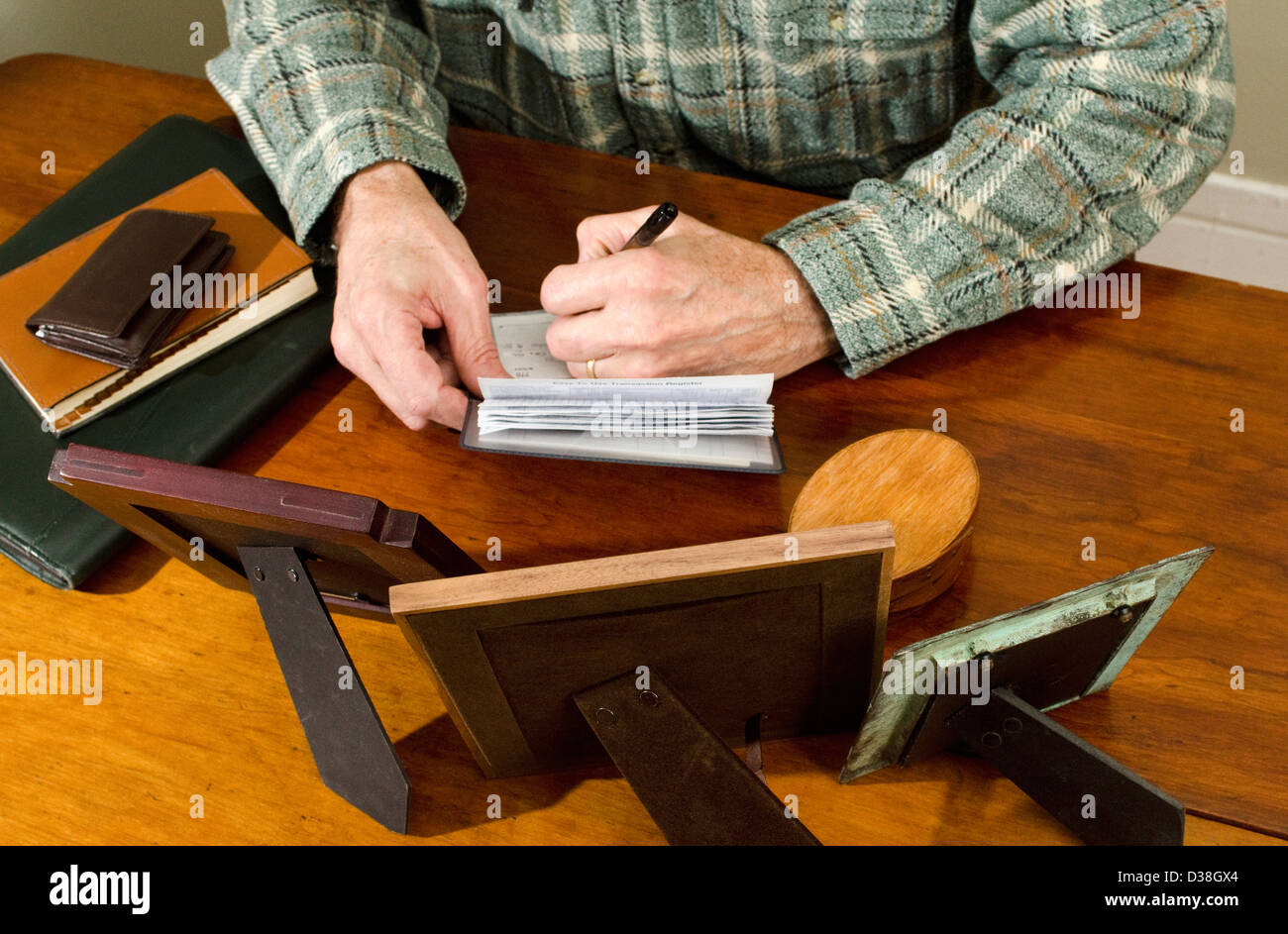 Hombre sentado en una mesa escribiendo verificar con chequera Foto de stock