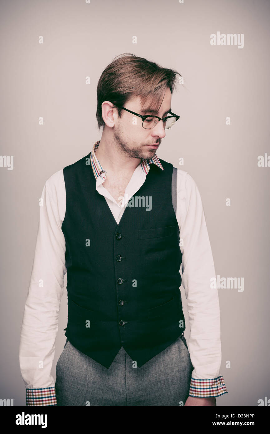 Hombre en veinte años en chaleco negro, camisa blanca, pantalón gris y gafas mira pensativo de stock - Alamy